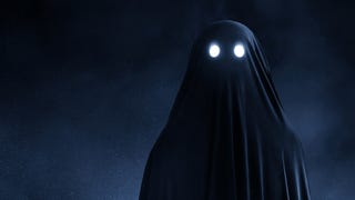 A photograph of a classic person-wearing-a-sheet ghost, but the sheet is almost black and the eyes are shining.