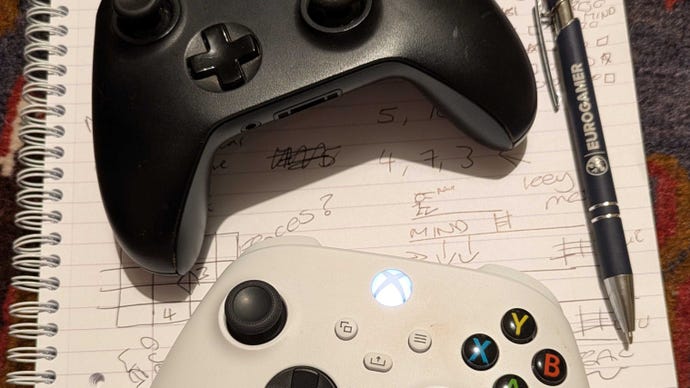 A photograph taken by Eurogamer's Victoria showing two Xbox controllers on a notepad that has some puzzle solutions written on it. A Eurogamer branded pen is artfully included in the tableau.